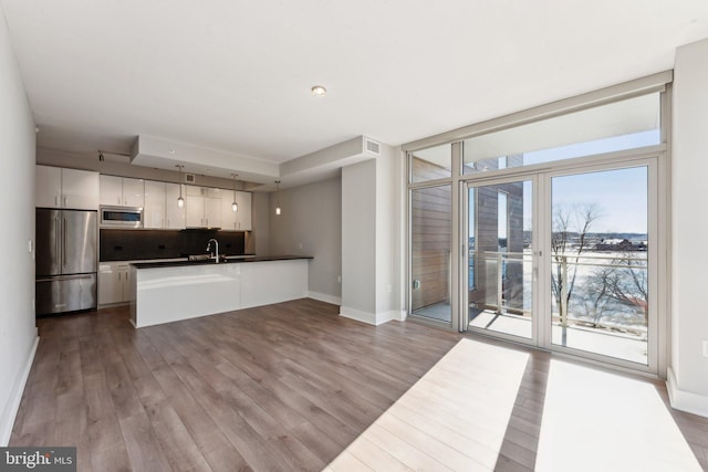 kitchen featuring stainless steel appliances, white cabinetry, hardwood / wood-style flooring, kitchen peninsula, and decorative backsplash