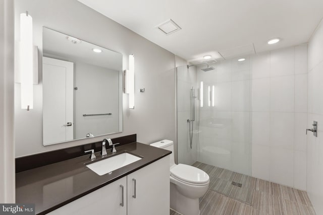 bathroom with toilet, vanity, and tiled shower