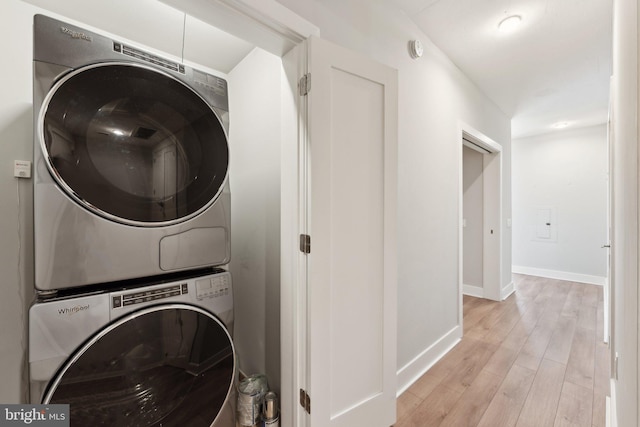 washroom with light wood-type flooring and stacked washer / drying machine