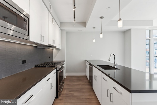 kitchen with decorative light fixtures, stainless steel appliances, white cabinetry, and sink