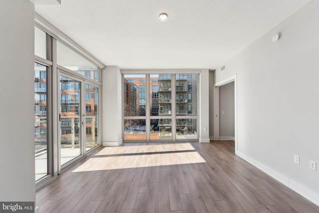 empty room with hardwood / wood-style floors and expansive windows