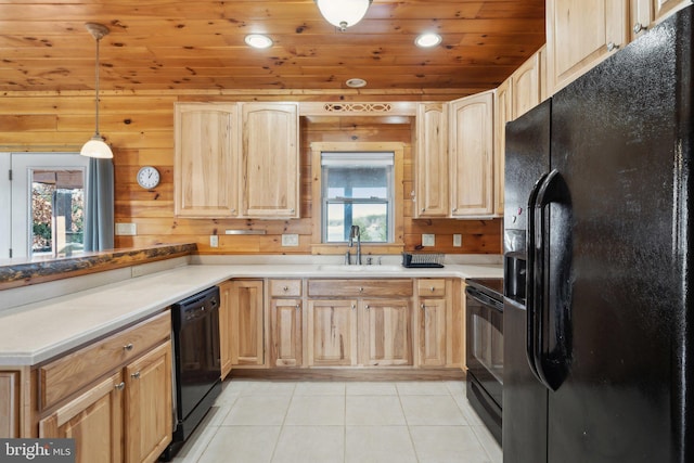 kitchen with wooden walls, light brown cabinetry, hanging light fixtures, and black appliances