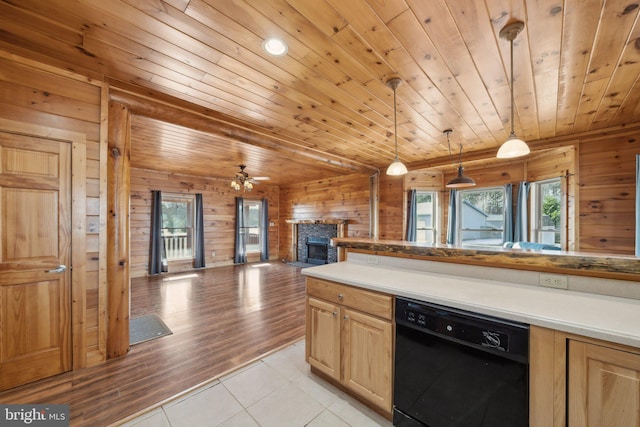 kitchen with decorative light fixtures, black dishwasher, light brown cabinetry, wood walls, and light tile patterned floors