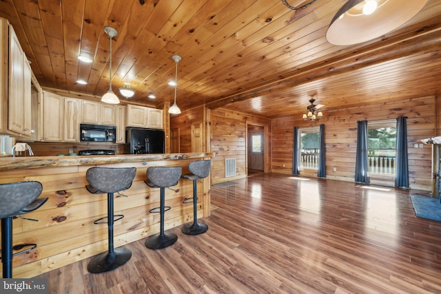 kitchen featuring wood ceiling, kitchen peninsula, wooden walls, a kitchen breakfast bar, and black appliances