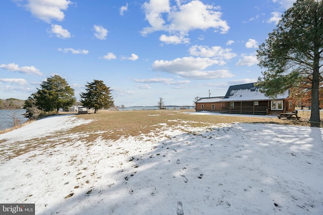 yard layered in snow with a water view and a sunroom