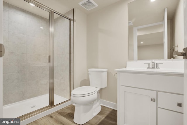 bathroom featuring vanity, toilet, a shower with door, and hardwood / wood-style floors