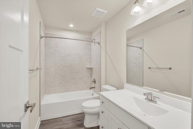 full bathroom featuring vanity, tiled shower / bath, wood-type flooring, and toilet