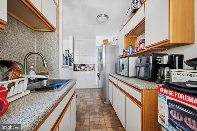 kitchen with sink, stainless steel appliances, and white cabinetry