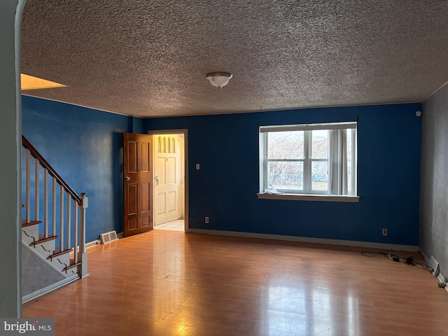 unfurnished room featuring hardwood / wood-style flooring and a textured ceiling