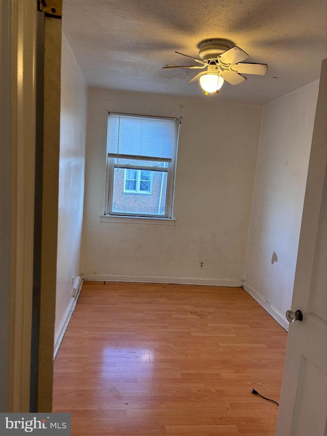 unfurnished room featuring light wood-type flooring, ceiling fan, and a textured ceiling