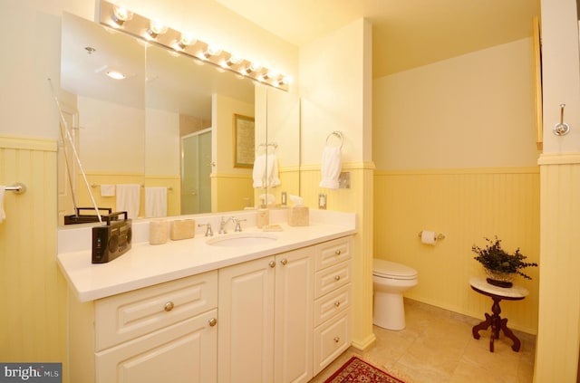 bathroom featuring toilet, tile patterned flooring, walk in shower, and vanity