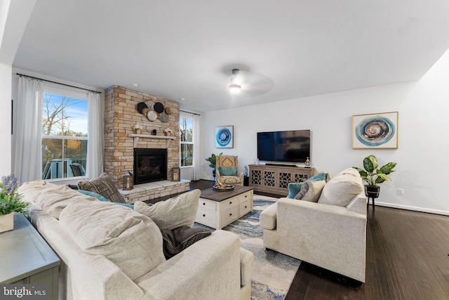 living room with ceiling fan, a fireplace, a wealth of natural light, and dark wood-type flooring