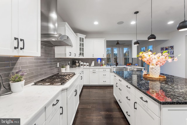 kitchen with stainless steel gas stovetop, white cabinetry, wall chimney exhaust hood, and sink