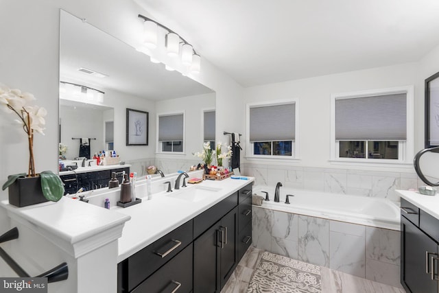 bathroom featuring tiled tub and vanity