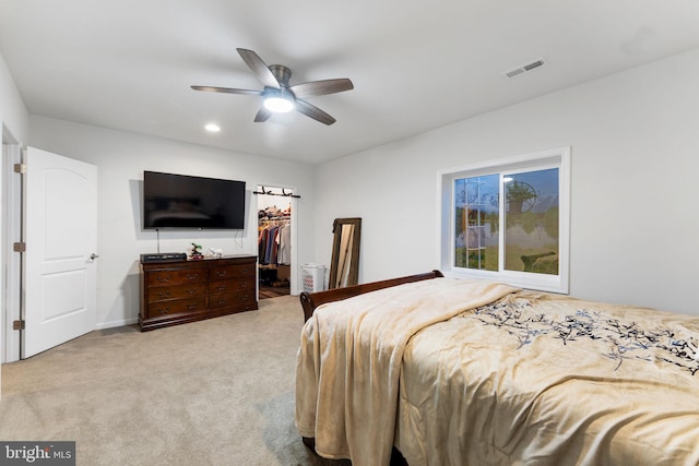 carpeted bedroom with ceiling fan, a closet, and a walk in closet