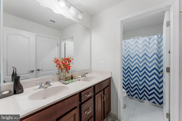 bathroom with toilet, vanity, tile patterned flooring, and walk in shower