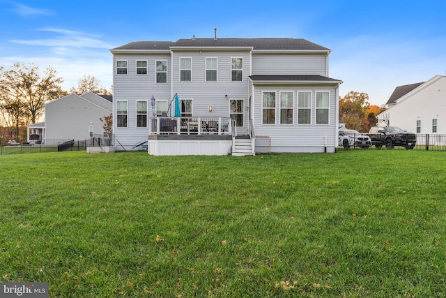 rear view of property with a wooden deck and a lawn