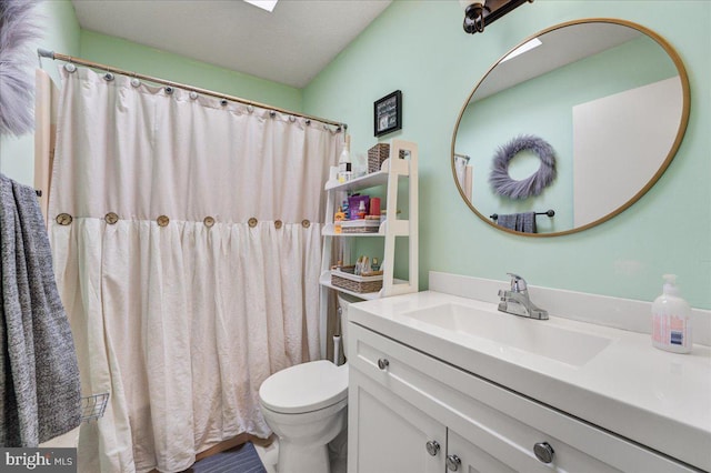 bathroom featuring a textured ceiling, curtained shower, vanity, and toilet