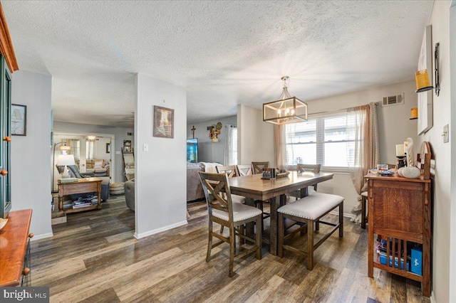 dining room featuring an inviting chandelier, a textured ceiling, and dark wood-type flooring