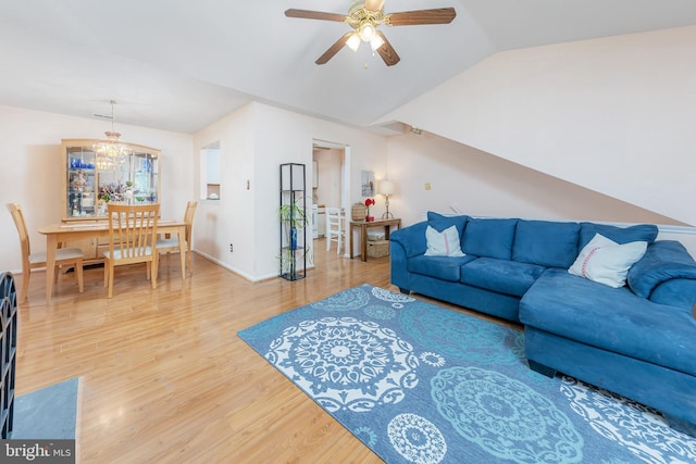 living room with lofted ceiling, hardwood / wood-style flooring, and ceiling fan with notable chandelier