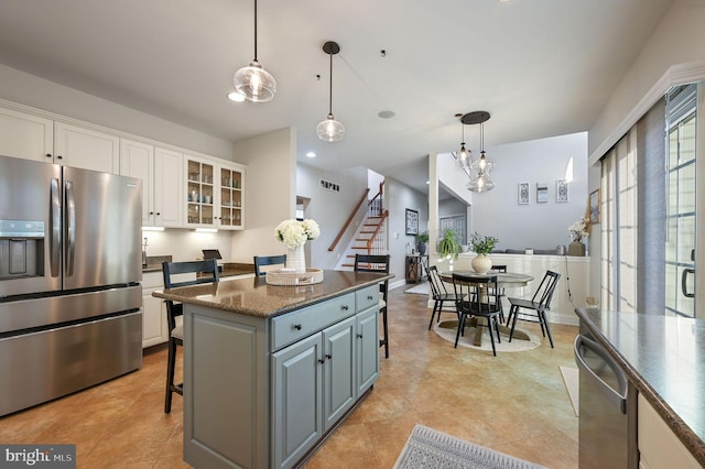 kitchen featuring stainless steel appliances, white cabinetry, a kitchen island, and hanging light fixtures