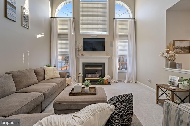 living room with a towering ceiling, light colored carpet, and a wealth of natural light