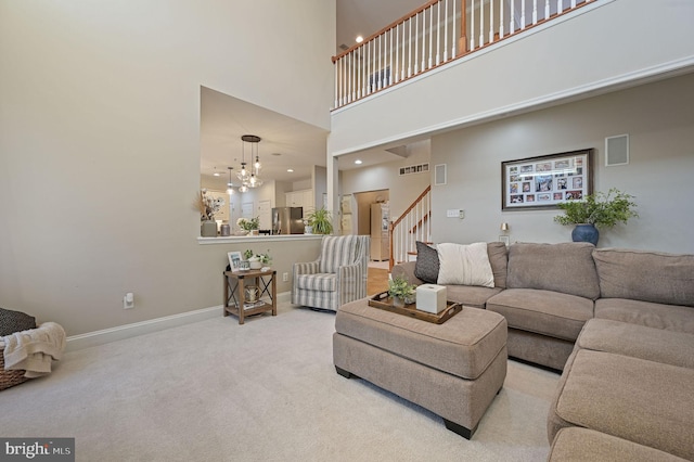 living room with a towering ceiling, an inviting chandelier, and light colored carpet