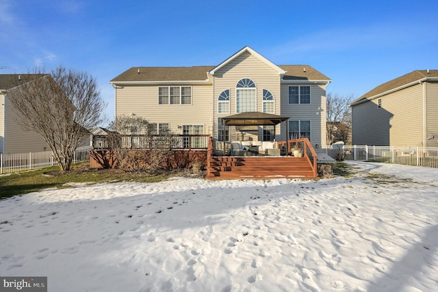 snow covered back of property featuring a gazebo and a deck