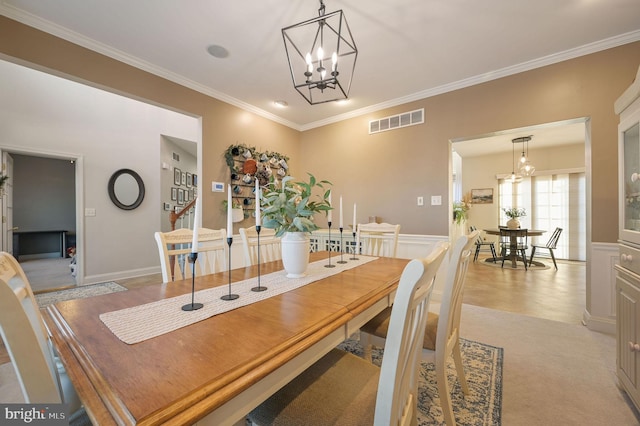 dining area featuring an inviting chandelier, light colored carpet, and ornamental molding