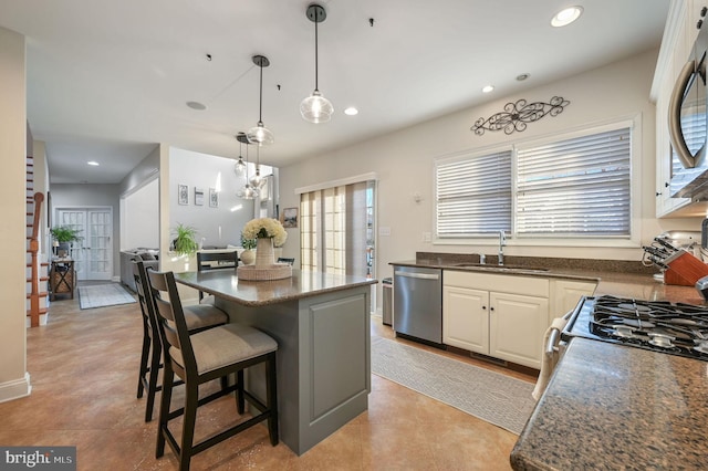 kitchen featuring pendant lighting, a kitchen bar, a kitchen island, appliances with stainless steel finishes, and sink