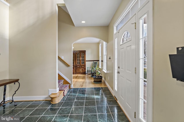 tiled entryway with arched walkways, recessed lighting, stairs, and baseboards