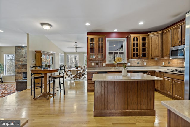 kitchen with appliances with stainless steel finishes, light countertops, a kitchen island, and backsplash