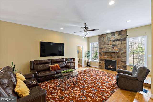 living area with a wealth of natural light, recessed lighting, wood finished floors, and a stone fireplace