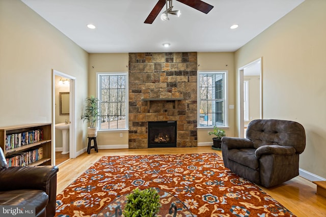 living area featuring a stone fireplace, wood finished floors, and a wealth of natural light