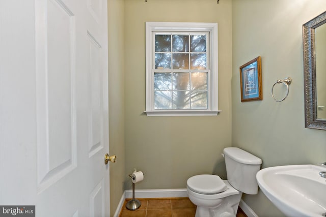 bathroom featuring toilet, tile patterned flooring, baseboards, and a sink