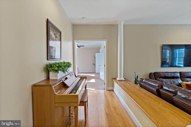 living room with baseboards, decorative columns, and light wood finished floors