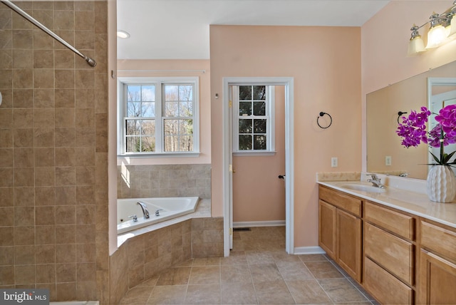 bathroom with tiled tub, tile patterned flooring, vanity, and baseboards