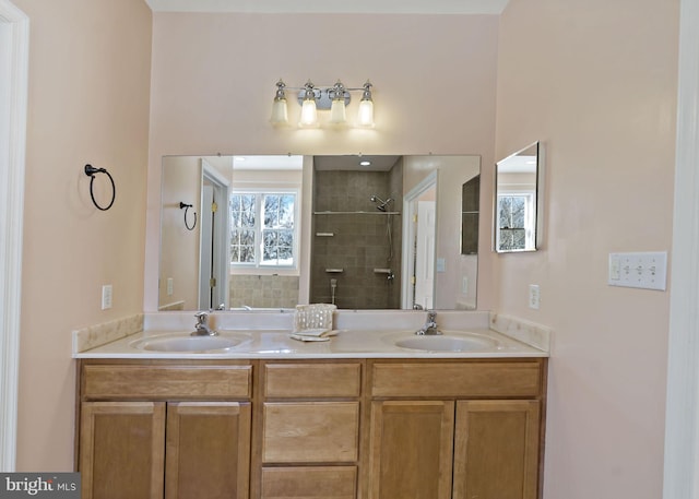 bathroom featuring a sink, a tile shower, and double vanity