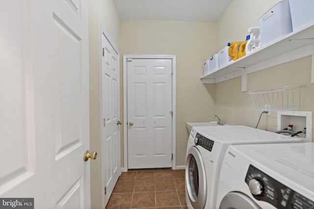 clothes washing area with a sink, washer and dryer, laundry area, dark tile patterned floors, and baseboards