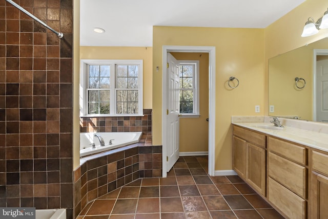 bathroom with tiled bath, baseboards, tile patterned flooring, and vanity