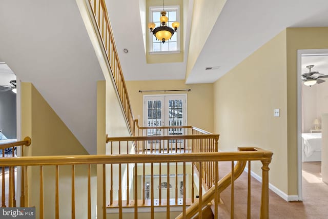 stairway with carpet, visible vents, baseboards, and ceiling fan with notable chandelier