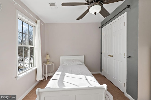 bedroom featuring a ceiling fan, visible vents, baseboards, a closet, and dark colored carpet