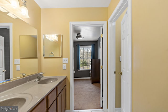 full bath featuring double vanity, baseboards, and a sink