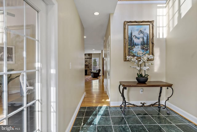 hall with dark tile patterned flooring, baseboards, and recessed lighting