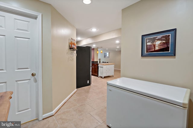 corridor featuring light tile patterned floors, baseboards, and recessed lighting