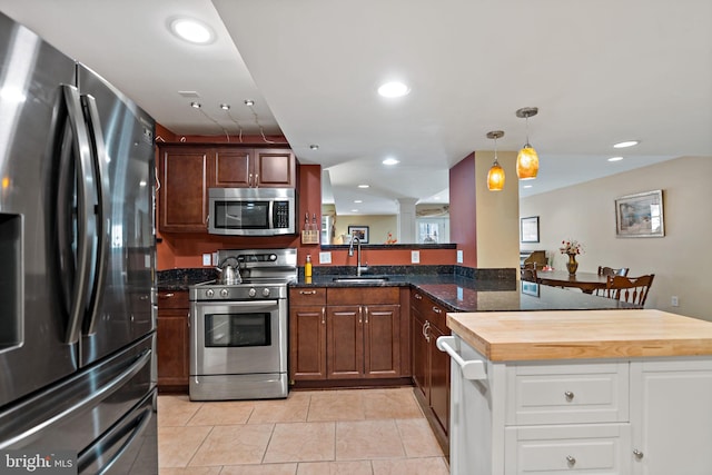 kitchen featuring stainless steel appliances, recessed lighting, a sink, a peninsula, and ornate columns