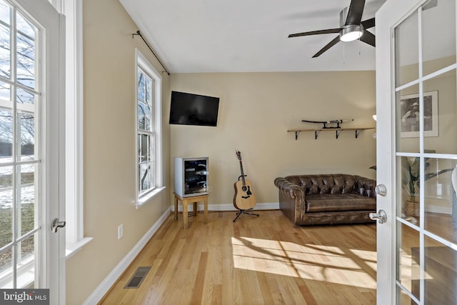 sitting room with french doors, visible vents, ceiling fan, wood finished floors, and baseboards