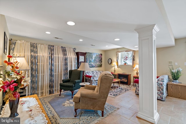 living area featuring ornate columns, visible vents, a glass covered fireplace, and recessed lighting