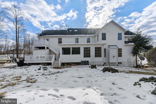 snow covered rear of property with cooling unit and a wooden deck