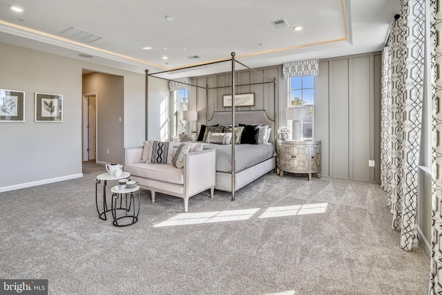 bedroom featuring a raised ceiling, multiple windows, and light colored carpet